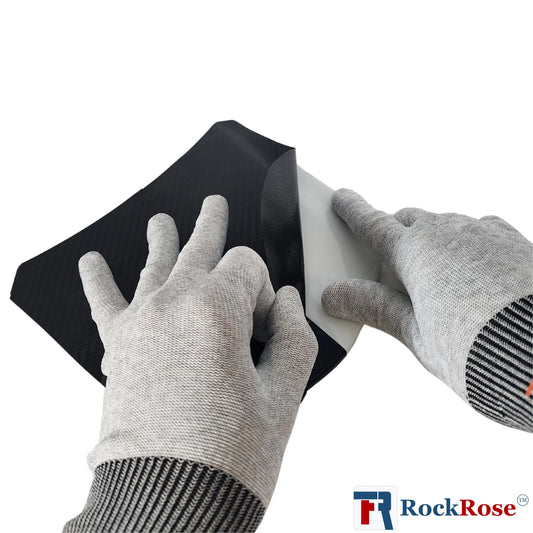 Person wearing gray gloves applying black vinyl wrap to a white surface with RockRose logo.