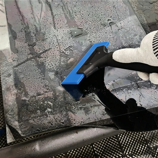 A gloved hand using a blue and Premium HD Plastic Handle Squeegee Tool to remove water from a glossy, wet surface.