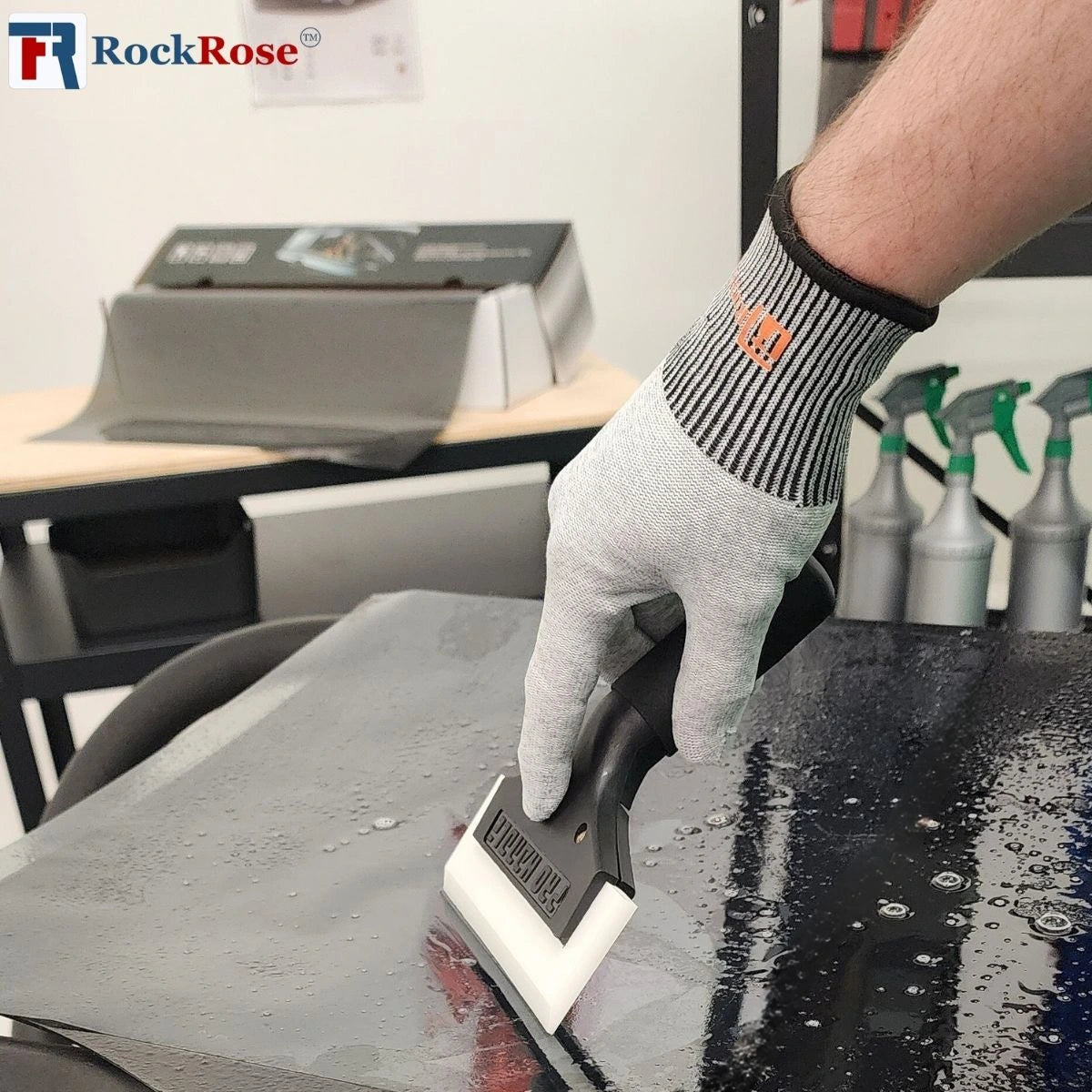Black Cast aluminum squeegee with white tint scraper on a black surface wearing gloves