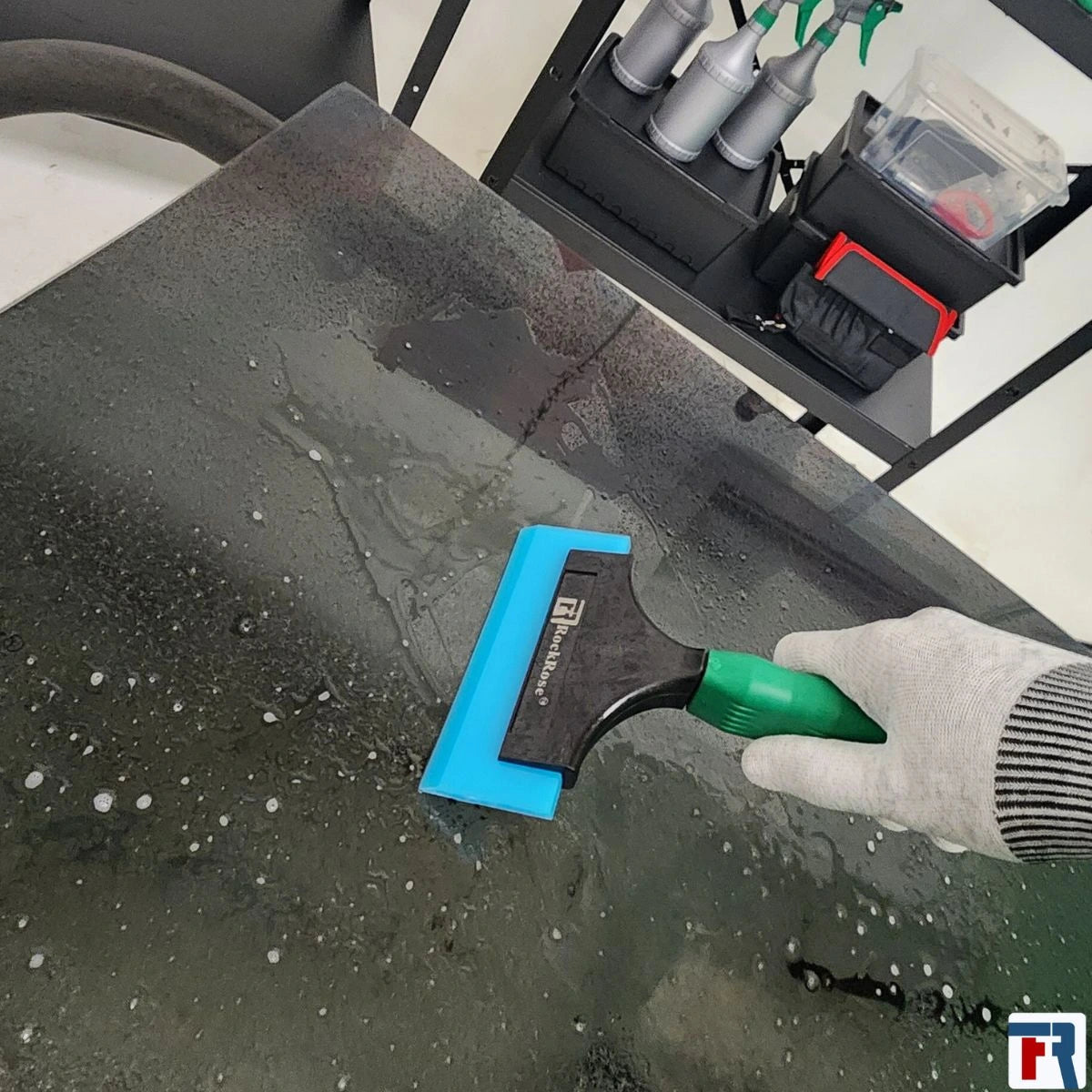 Holding a blue squeegee using a glove with yellow tint scrapper and rockrose logo 