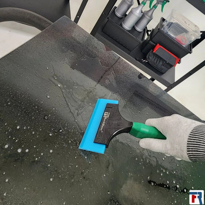 Holding a blue squeegee using a glove with yellow tint scrapper and rockrose logo 