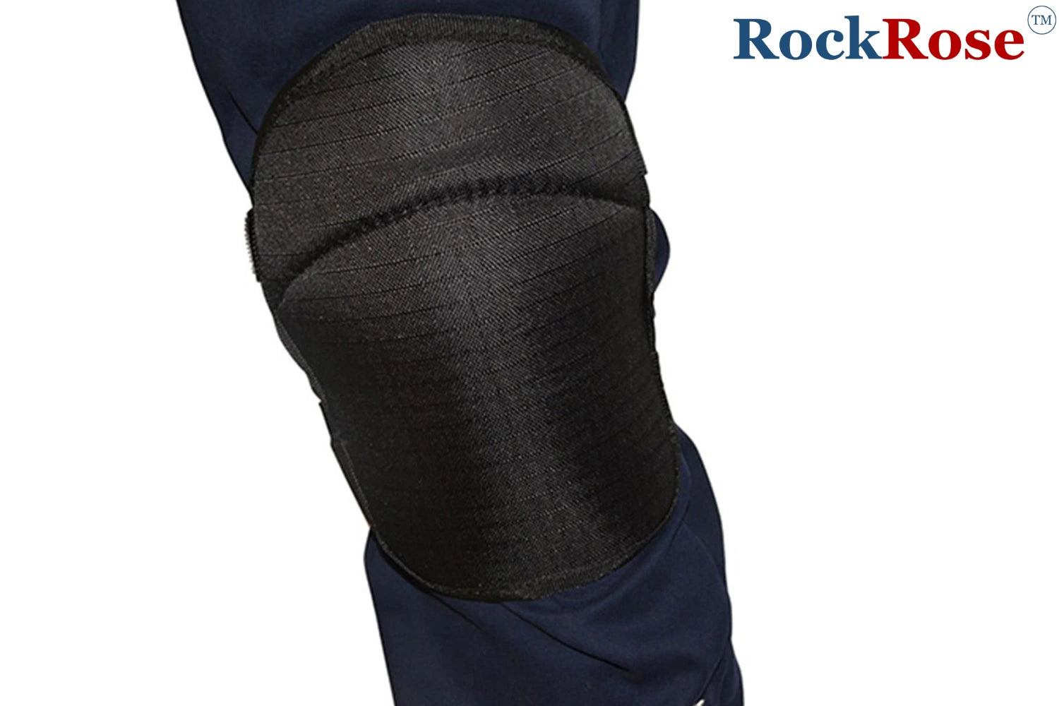 A close-up of a knee pad in black textured mesh or fabric, worn over dark navy pants, with the RockRose brand logo in the top right corner.
