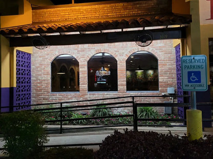 Brick building with arched windows and a reserved parking sign for disabled access.