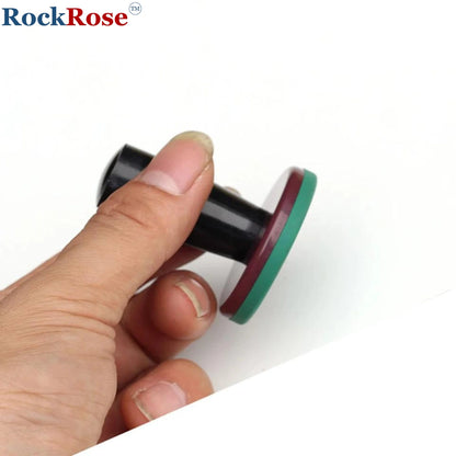 Hand holding a black and green magnet against a white background with 'RockRose' branding.