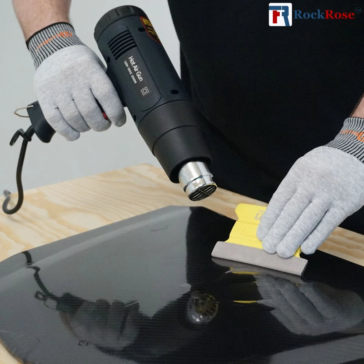 Person using a heat gun on a car window with RockRose logo in the corner