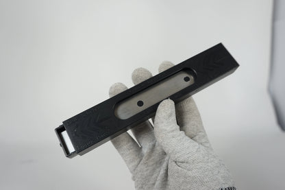 Hand holding a black metal tool against a light gray background