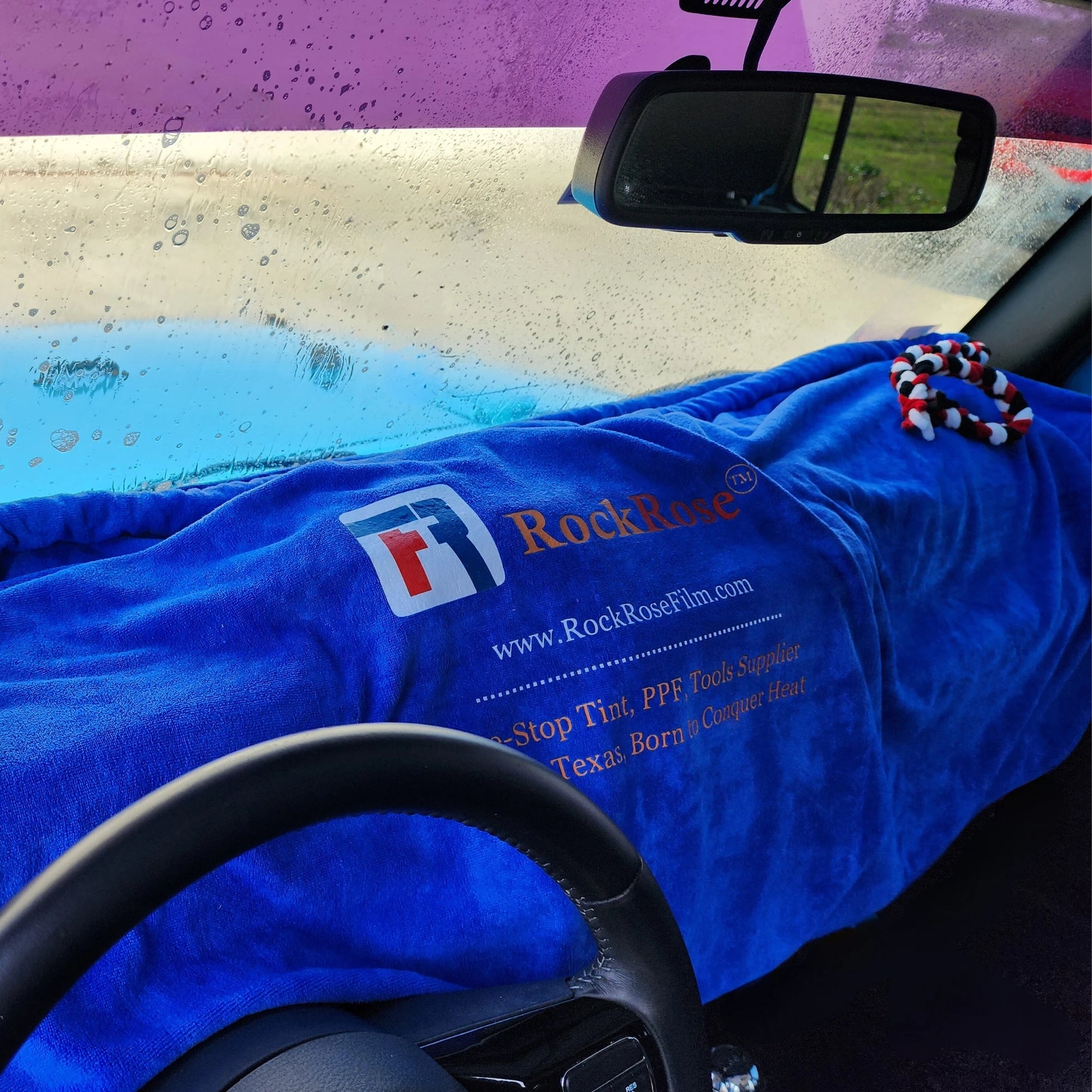 A blue dashboard cover with a patterned edge, branded with the RockRose logo, laid out inside a car interior