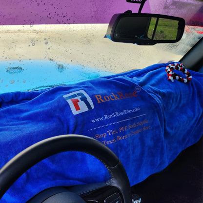 A blue dashboard cover with a patterned edge, branded with the RockRose logo, laid out inside a car interior