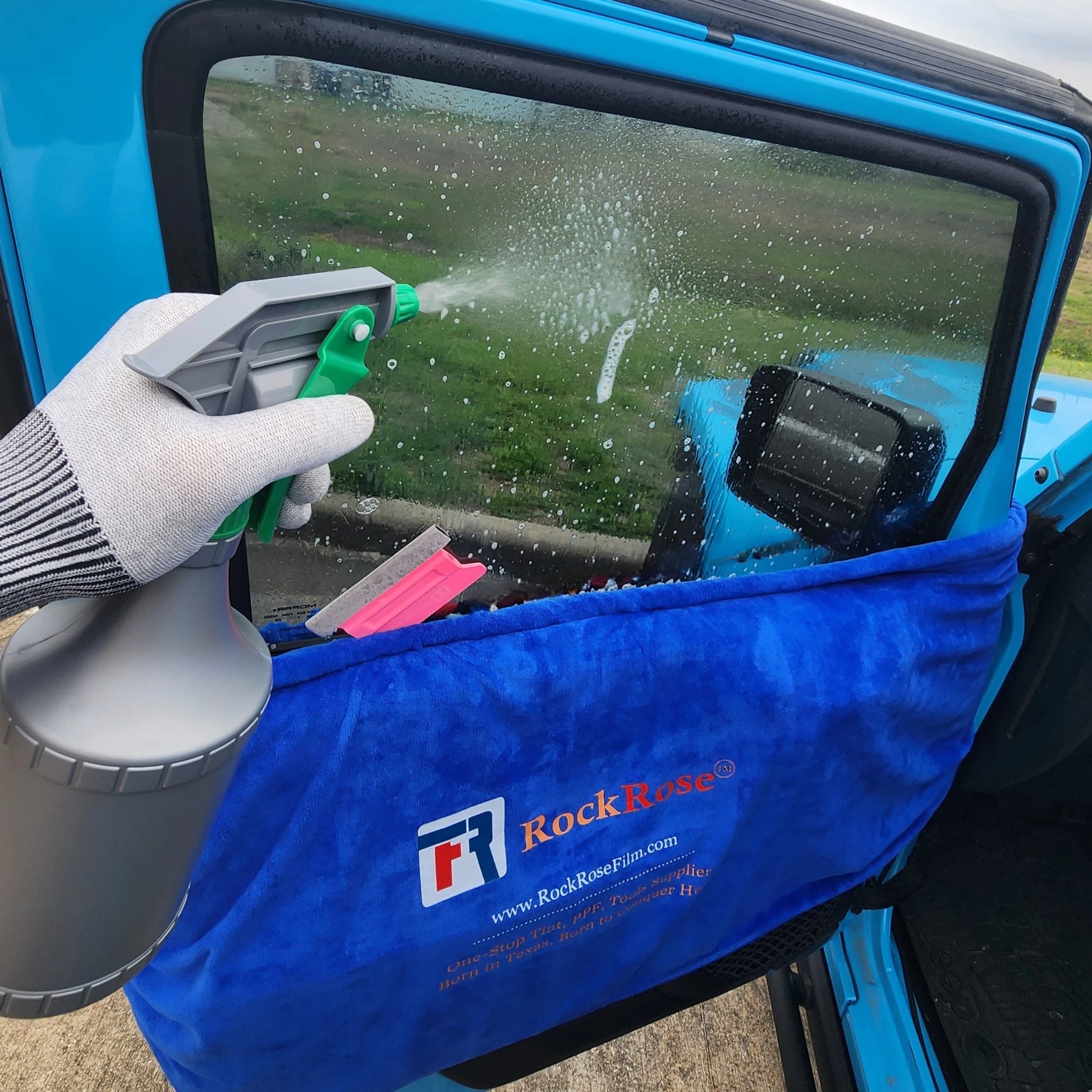 A blue dashboard cover with a patterned edge, branded with the RockRose logo, laid out on below a car window tint