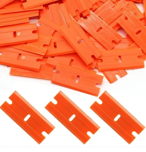 Pile of orange plastic razor blades on a white background