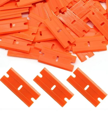 Pile of orange plastic razor blades on a white background