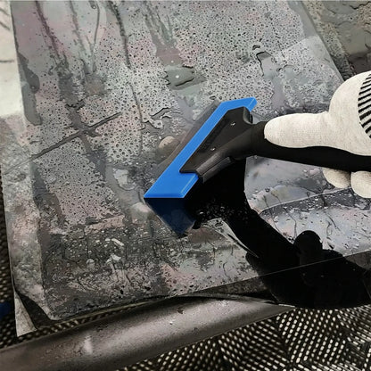 A gloved hand using a blue and Premium HD Plastic Handle Squeegee Tool to remove water from a glossy, wet surface.
