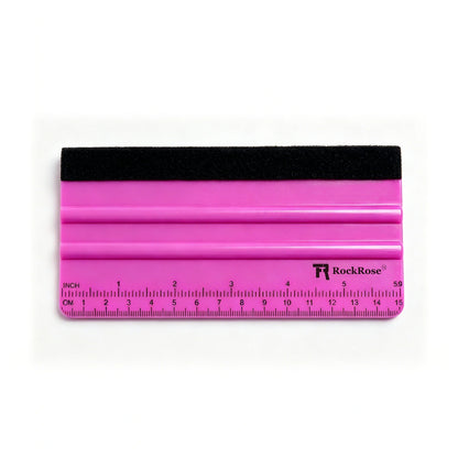 A RockRose plastic squeegee with a bright pink body, a black rubber edge, and a clear ruler printed along the bottom, shown on a white background.