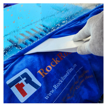 Person applying a white squeegee on a blue surface with 'RockRoseFilm' branding.