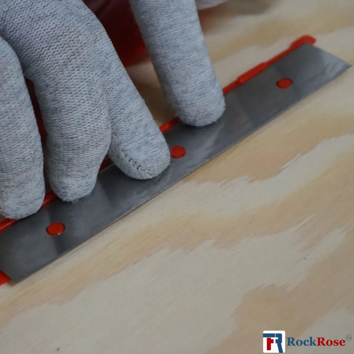 Person using a Stainless Steel Double-Edge Razor Blades tool on a wooden surface with 'RockRose' branding.