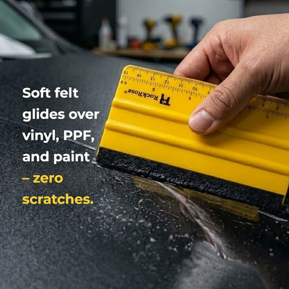 A hand holds a yellow Rockrose squeegee with a black rubber edge against a dark car surface, demonstrating its use. White text on the left reads 'Soft felt glides over vinyl, PPF, and paint - zero scratches.