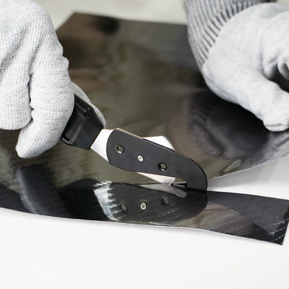 Person using a single vinyl cutter tool to black vinyl wrap on a surface