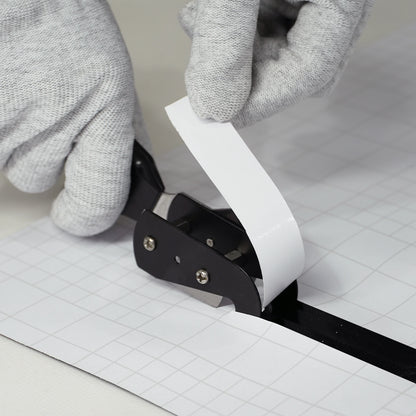 Person using a paper cutter slitter tool with gloves on a grid background