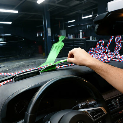 cleaning a car's dashboard with a green brush and a colorful braided rope on a garage