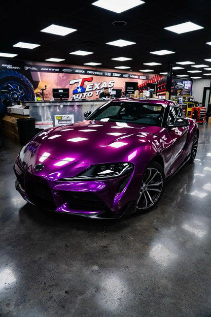 Purple sports car in a showroom with 'Texas Auto Body' in the background color pansy