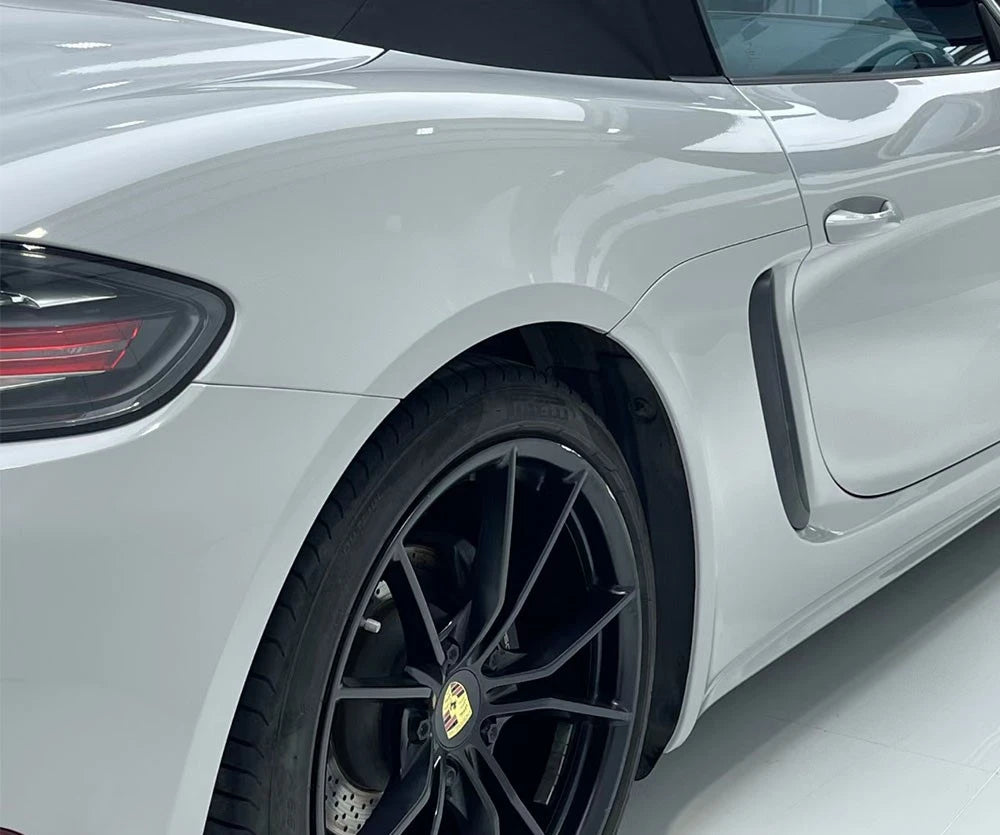 Close-up of a white car's side with black wheel and visible brand logo.